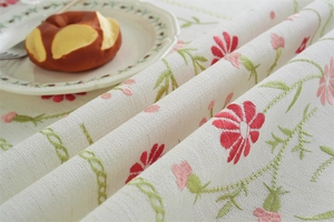 Close-up of red and pink daisy floral embroidery on vintage jacquard tablecloth fabric