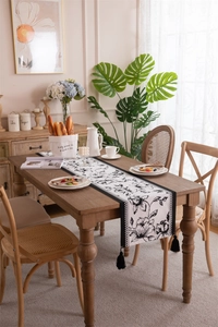 Close-up detail of black and white floral jacquard table runner with black handmade tassels