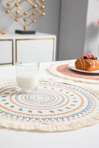 Détail d'un set de table bohème rond avec pompons et motifs géométriques