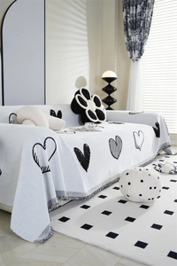 Detailed texture of white chenille sofa cover with black heart pattern and decorative fringe