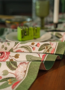 Dettaglio del runner da tavolo con motivo floreale rosso jacquard e trama in poliestere
