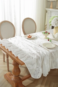 Détail d'une nappe en dentelle jacquard fleurie avec des bords à volants sur table en bois