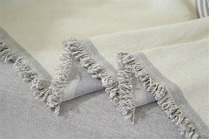 Détail du jeté de canapé en chenille avec texture tissée crème et bordure à franges