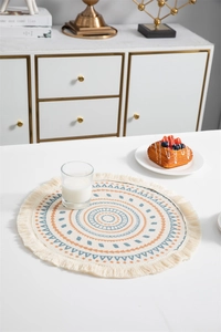 Détail d'un set de table boho rond avec motifs géométriques et bordures à franges