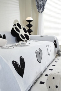 Detail of chenille sofa cover with black and white heart pattern and grey fringe edge