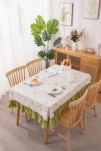 Close-up of floral embroidery on cotton tablecloth with olive green ruffled edges