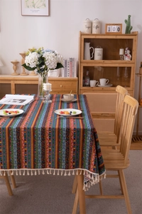 Detailed view of bohemian striped tablecloth with multi-color ethnic patterns and white tassels
