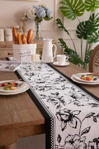 Macro view of floral table runner with black hand-drawn patterns and checkered borders