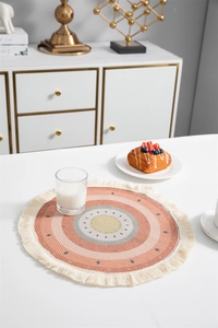 Détail de set de table bohème rond avec motifs géométriques pastel et franges
