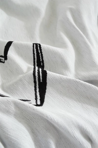 Macro shot of white chenille fabric with black dot patterns and fine jacquard texture