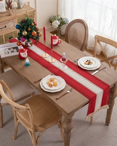 Close-up of crochet Christmas table runner with red and cream patterns and tassels