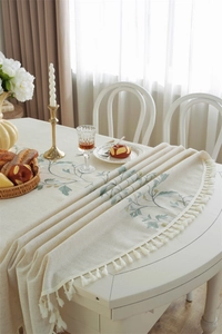 Close-up of elegant cream table cloth with floral embroidery and white fringe tassels