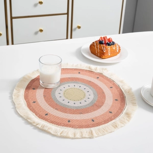 Vue de dessus du set de table bohème rond en coton avec motifs colorés et pompons crème
