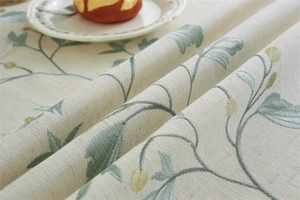 Macro detail of beige jacquard tablecloth with delicate floral embroidery and leaf patterns