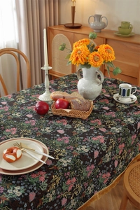 Close-up of vintage floral jacquard tablecloth with yellow tassel fringe in a cozy setting