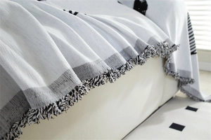 Detail of chenille sofa cover showing black and white polka dot pattern and tassel fringes