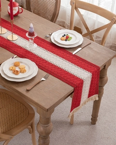 Close-up of red and white woven Christmas table runner with lace crochet and tassels