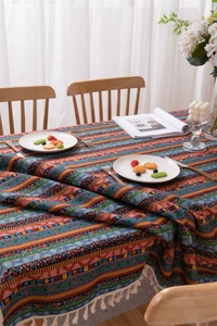 Close-up of bohemian tablecloth with colorful geometric stripes and white tassels