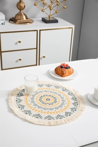 Détail d'un set de table bohème rond avec pompons en coton et motifs de mandala