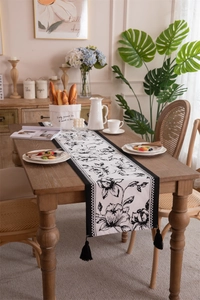 Detail of floral table runner with black and white checkered border and long tassels