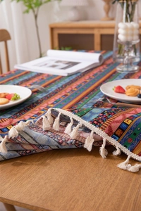 Detail of bohemian striped tablecloth with cotton tassels in a cozy home dining setting