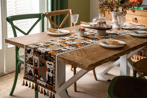 Detail of Halloween table runner with orange pumpkin and bat motifs and fringe tassels