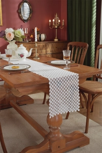 Detail of white hollow floral lace table runner with milk silk embroidery on wood table