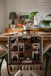 Detail of Halloween table runner with woven pumpkin motifs and bicolored tassel accents