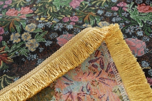 Detailed close-up of vintage floral jacquard fabric with elegant golden fringe trim