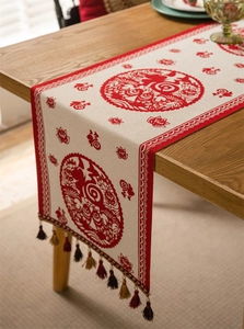 Detail of red jacquard table runner with Fu character patterns and multicolor tassels
