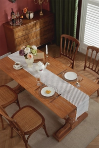 Detail view of white lace table runner with hollow crochet floral patterns on wooden table