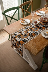 Detail of Halloween table runner with pumpkin patterns, jacquard fabric, and fringe edges