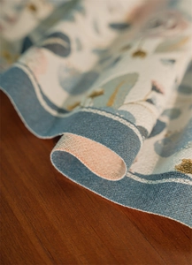 Dettaglio del runner da tavolo jacquard con margherite su tavolo in legno di noce