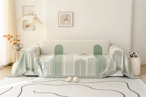 Close-up of beige Nordic chenille throw blanket with green geometric patterns and tassels