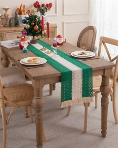 Detailed crochet texture of green and white striped table runner with cream tassels