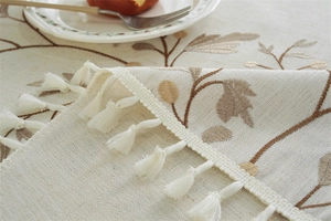 Close-up of floral embroidery and delicate white tassel fringe on the table runner
