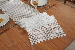 Close-up of white lace table runner with circular hollow patterns on a wooden table