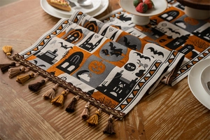 Detail of Halloween table runner with pumpkins and bats motifs featuring orange tassels