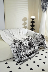 Detail of chenille sofa cover showing tropical leaf patterns and black-and-white tassels