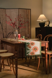 Dettaglio di runner da tavolo tessuto con jacquard a margherite arancioni e nappe verdi