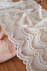 Detailansicht eines weißen Spitzen-Tischläufers mit feinem Häkelmuster und Textur