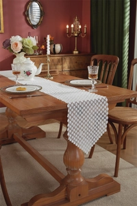 Close-up of white hollowed-out lace table runner with intricate floral patterns