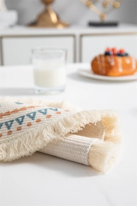 Gros plan du set de table en coton avec texture tissée et détails de franges