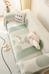 Detail of Nordic chenille sofa throw with green geometric patterns and soft fringe trim