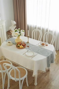Detailed macro view of vintage floral embroidery and white fringe tassels on linen tablecloth