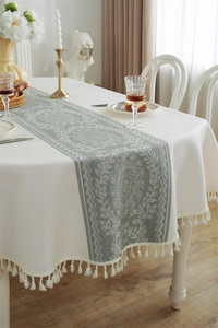 Detailed view of vintage jacquard tablecloth featuring floral patterns and elegant tassels