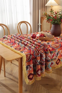 Detailed close-up of bohemian floral jacquard fabric with golden tassel fringe edge