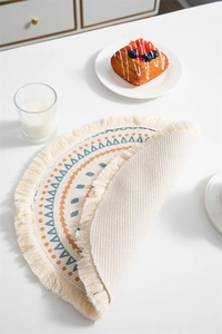 Détail macro d'un set de table rond bohème avec des pompons fins et des motifs tissés