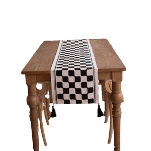 Checkered black and white table runner with tassels on a dark wood dining table