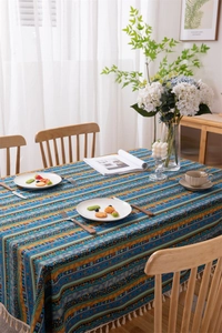 Detail of bohemian colorful striped tablecloth with white tassel edges and woven texture